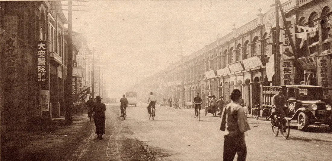 1920 年代大稻埕太平町的街景,左側騎樓掛著直立招牌「大安醫院」,路上有人騎腳踏車,右邊停著一輛老汽車